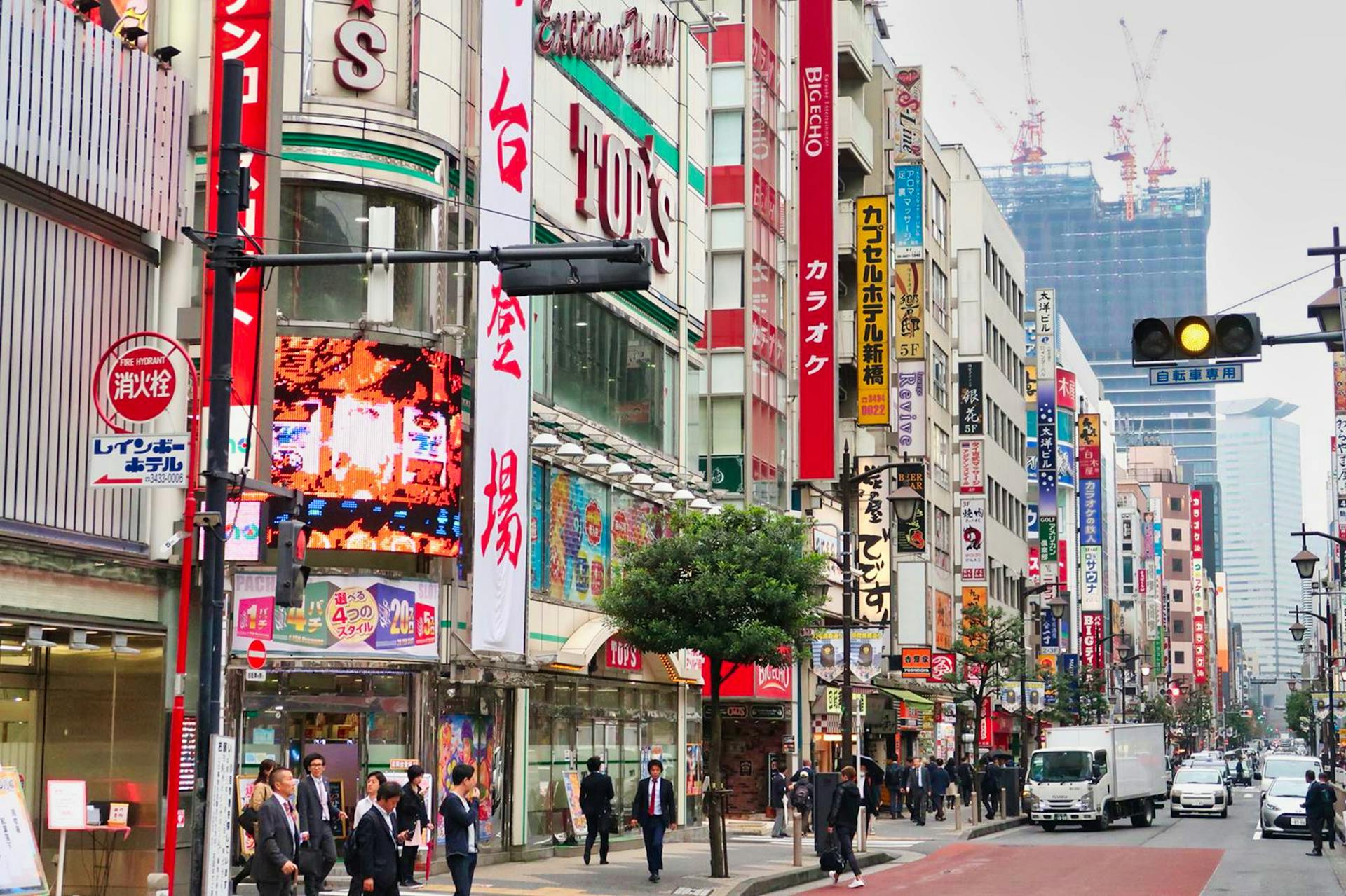 Bustling city street in Shinjuku, Tokyo with neon signs and people.