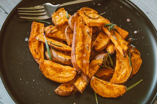 Free Close-up of crispy sweet potato wedges topped with rosemary, perfect for a healthy snack. Stock Photo