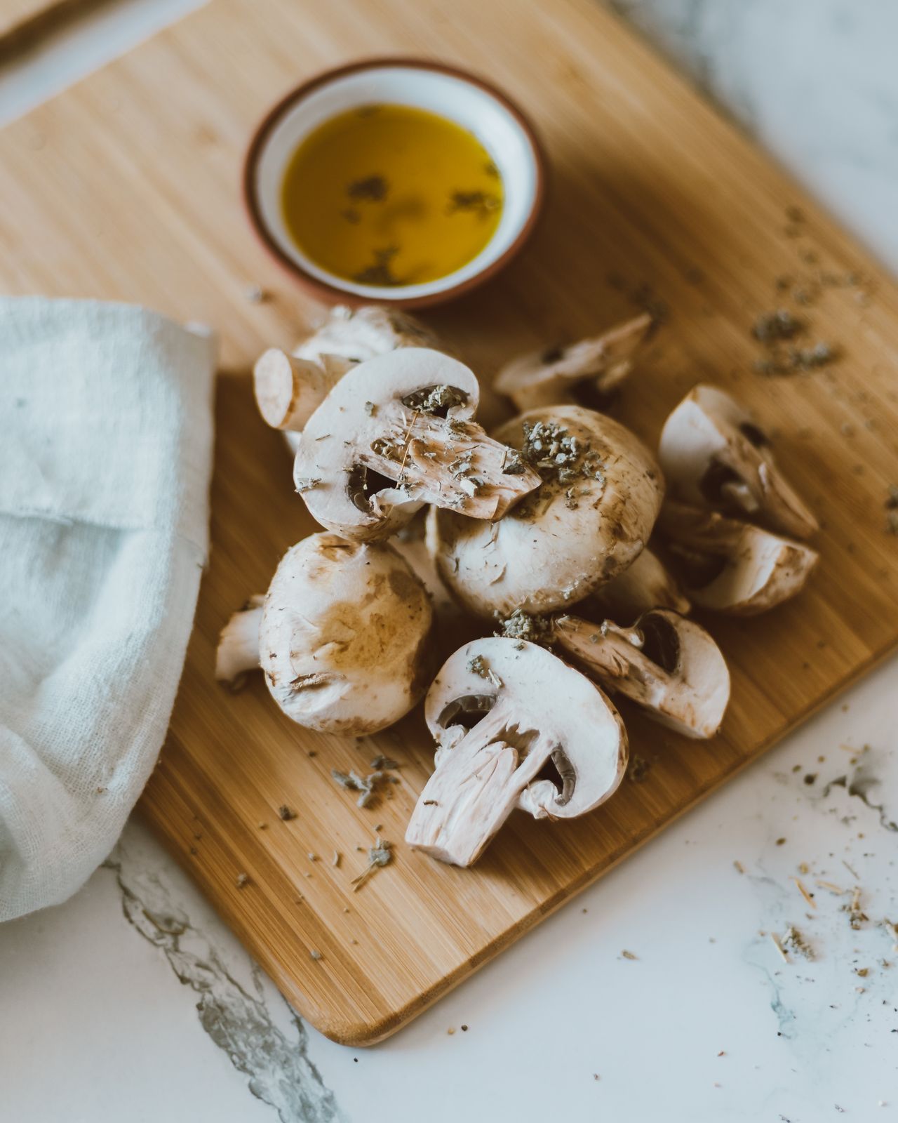 Sliced mushrooms with herbs and olive oil on a wooden board