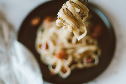 Enjoy a close-up view of a fork holding delicious pasta with blurred background, perfect for food lovers.