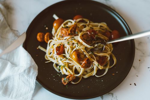 Free Delicious Italian linguine pasta with cherry tomatoes and herbs, beautifully plated for a food photograph. Stock Photo