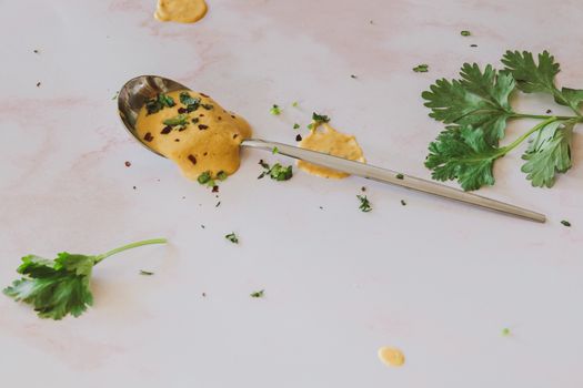 Spoonful of creamy herb sauce with fresh cilantro on a white background.