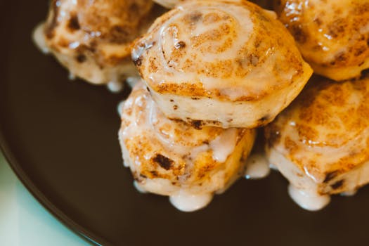 Delicious glazed cinnamon rolls stacked on a plate, perfect for breakfast or dessert.