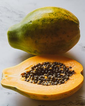 Close-up of ripe papaya cut open on a marble surface, showcasing juicy seeds.