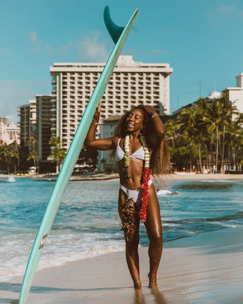 A Sexy Woman in White Bikini Holding a Surfboard at the Beach