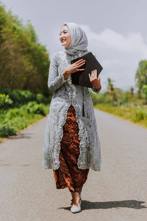 Woman in White Hijab and Brown Dress Holding Black Hat