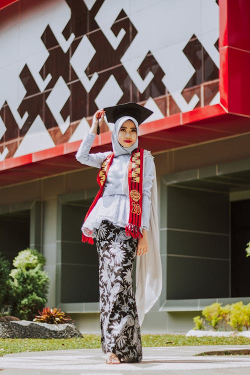 Woman in White Hijab Standing Near Red and White Wall