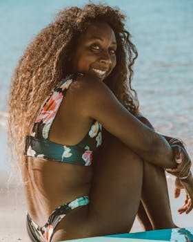 Smiling woman in floral bikini enjoying a sunny day at the beach.