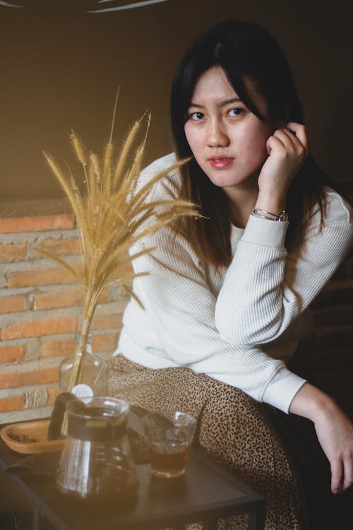 Woman in White Long Sleeve Shirt Sitting beside Black Table