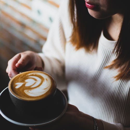 Woman in White Sweater Holding Cup of Cappuccino