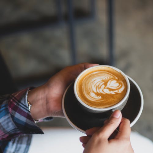 Close-Up Shot of a Person Holding a Cup of Cappuccino