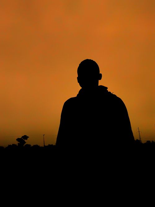 Free Silhouette of a person with an orange sunset sky backdrop, capturing the essence of twilight. Stock Photo