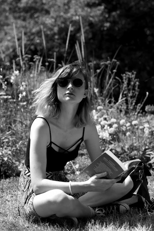Woman Sitting on Grass Reading Book