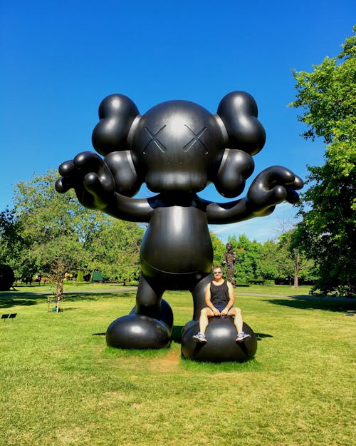 A Man Sitting on the Foot of a Giant Mouse Statue
