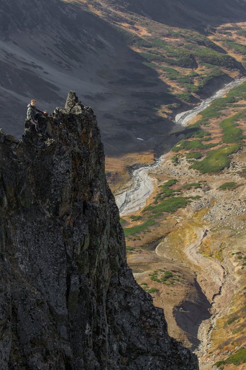 Free A Man Sitting on Top of a Rock Mountain Stock Photo