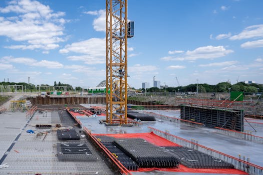 A vibrant construction site with a prominent yellow tower crane under a bright blue sky.