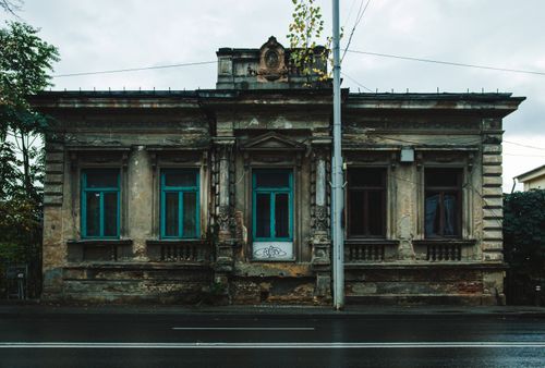 Free Capture of an old abandoned building with classic architectural details on a rainy urban street. Stock Photo