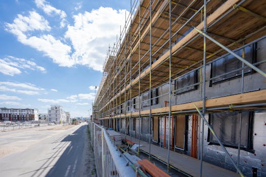Scaffolding on building facade at urban construction site under bright blue sky.