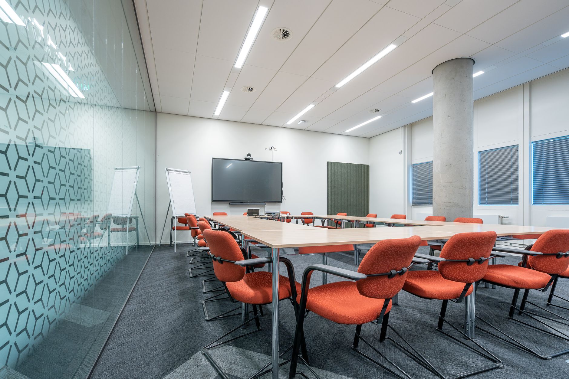 Spacious and stylish conference room featuring red chairs and a glass partition.