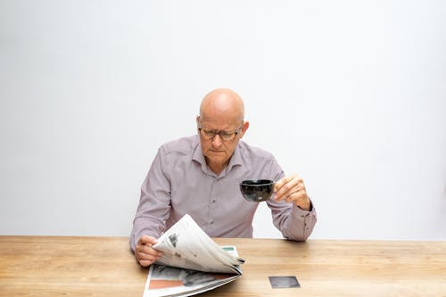 Free A Man Having Coffee While Reading the Newspaper Stock Photo