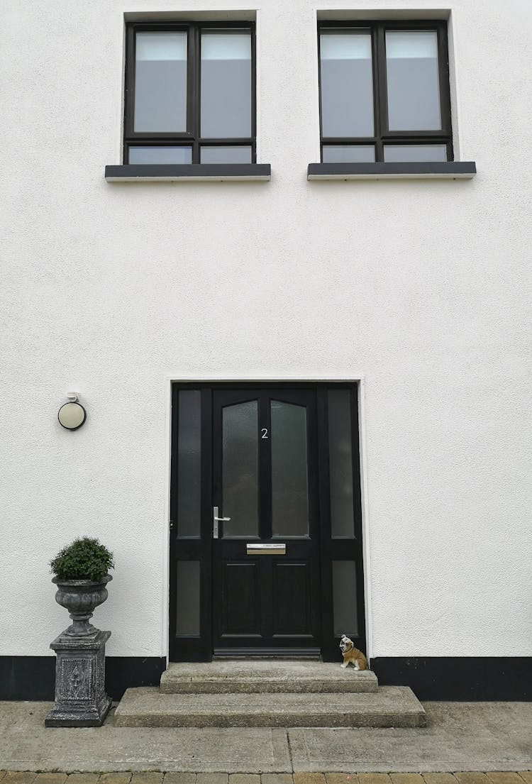 A Black Door On White House With Windows