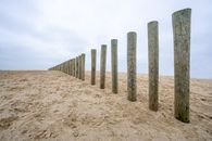 Brown Wooden Posts on Brown Sand Under White Sky