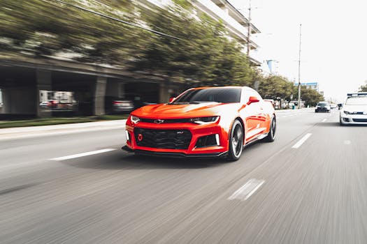 High-speed action shot of a red sports car racing through an urban environment, showcasing motion and modern design.