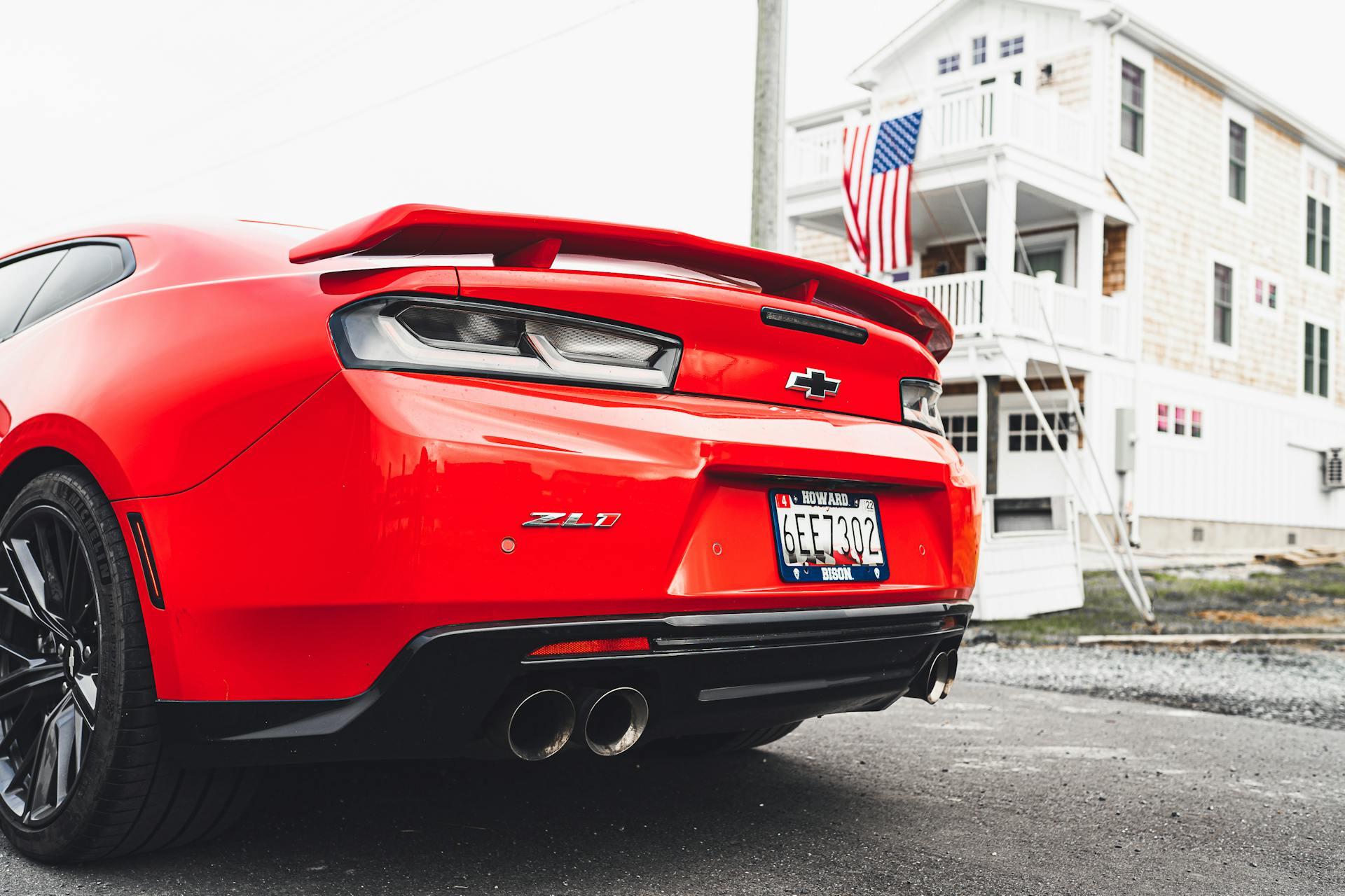 Vibrant red Chevrolet Camaro ZL1 parked outside a building with USA flag. Modern and powerful car design.