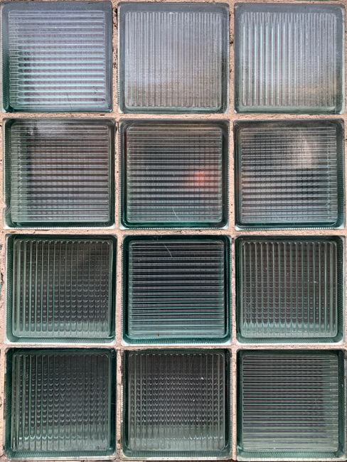 Close-up view of a textured glass block wall displaying symmetrical design and light play.