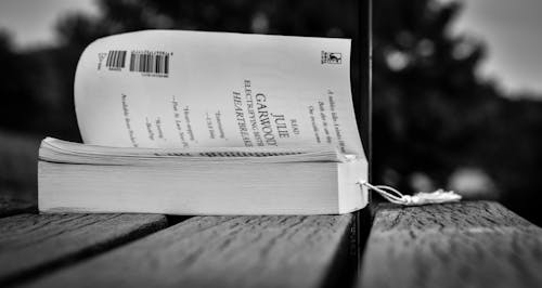 Opened book placed on wooden table in park