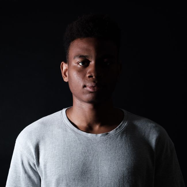 Portrait of young African American male in casual outfit looking at camera on black background