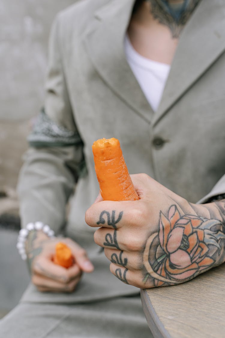 A Tattooed Person Holding A Carrot