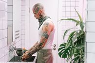 Man in Gray Tank Top Standing in Front of Green Plant