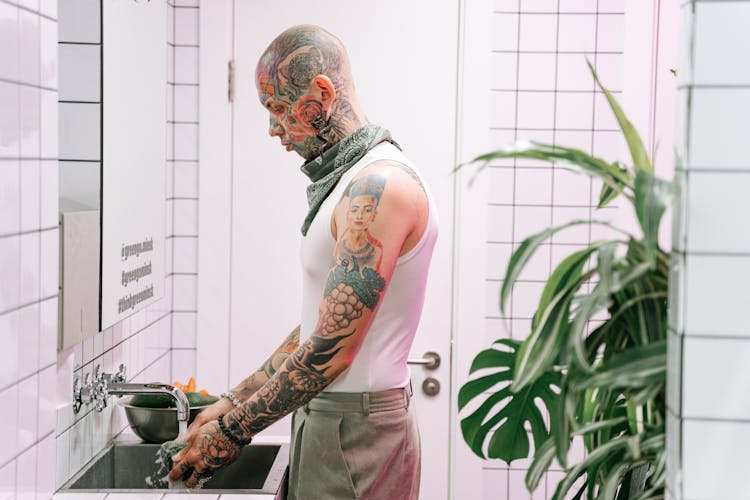 Man With Tattoos Washing Hands In Sink