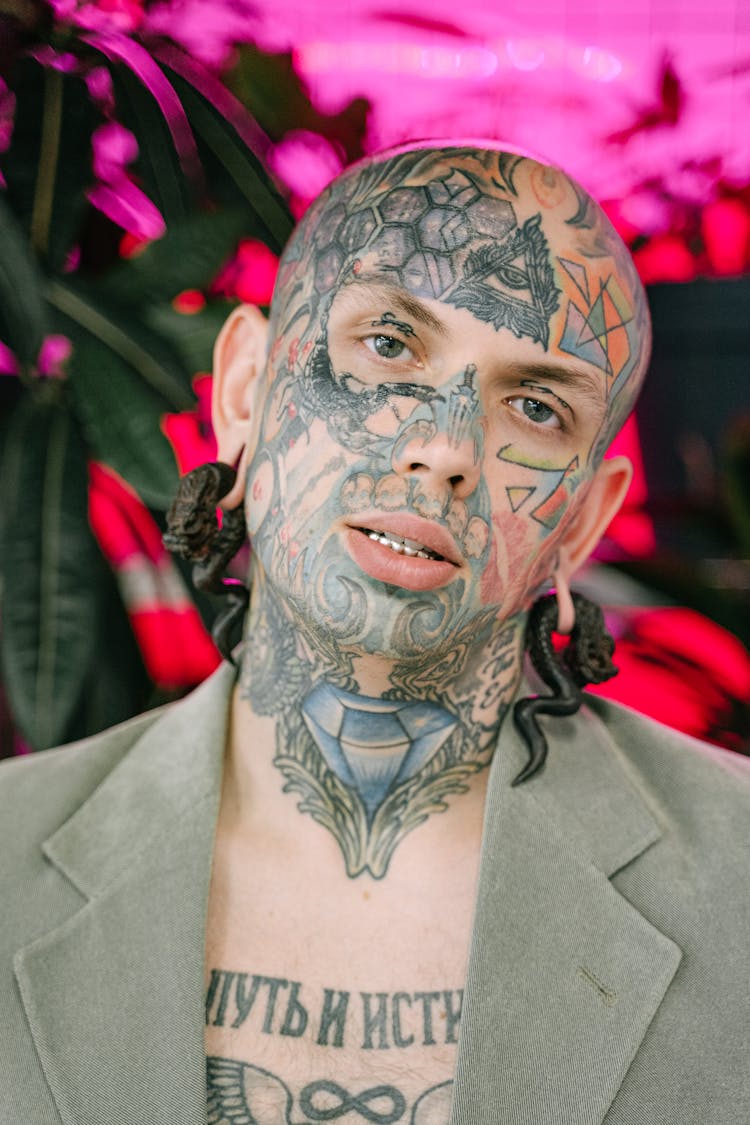 A Man With Face Tattoo Wearing Snake Earrings