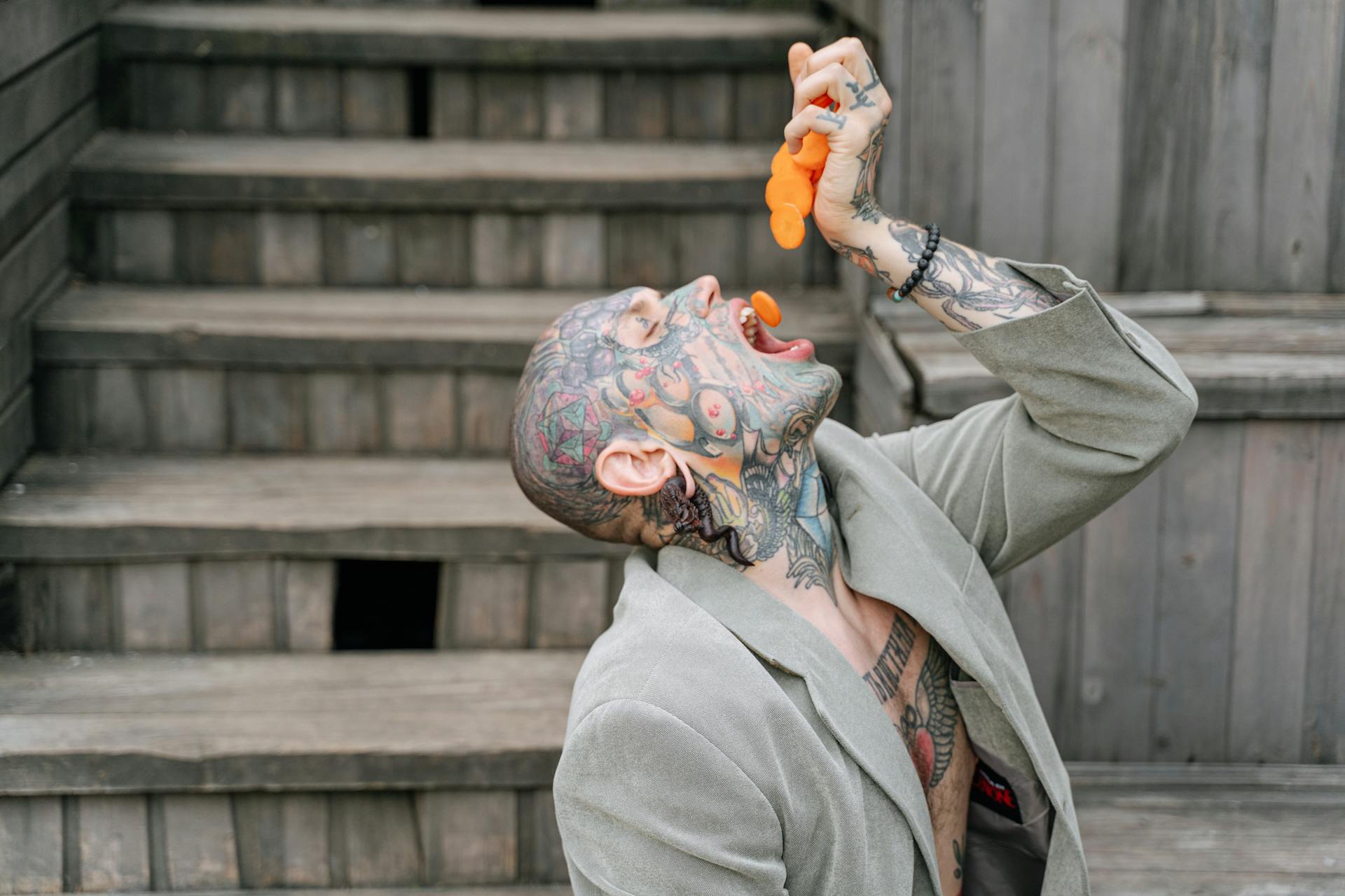 Tattooed Man in Gray Blazer Eating Carrots