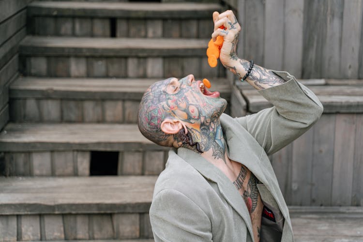 Tattooed Man In Gray Blazer Eating Carrots