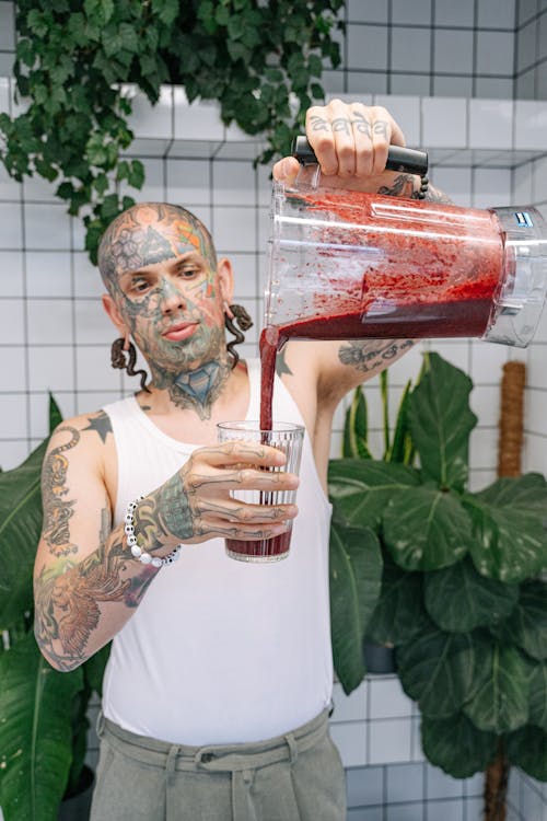 Man in White Tank Top pouring Smoothie on Glass