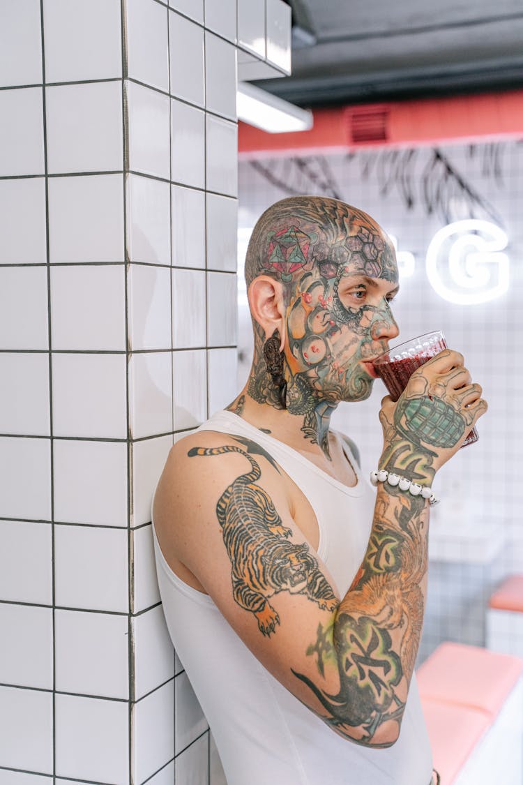 A Man In White Tank Shirt Top Drinking Beverage