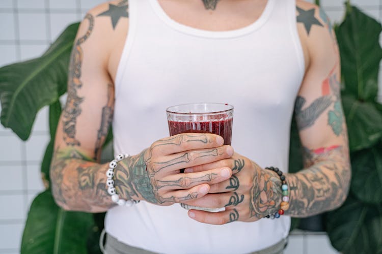 A Person In White Tank Shirt Top Holding A Glass Of Beverage
