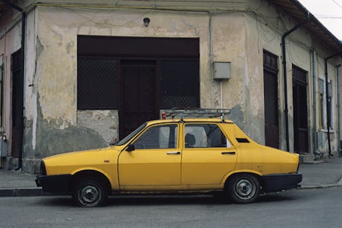 Yellow Car Parked Beside an Abandoned Building