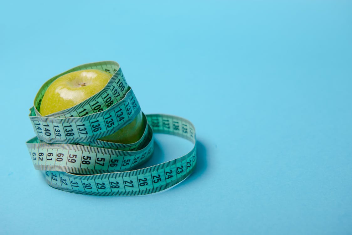 Apple with measuring tape on blue background