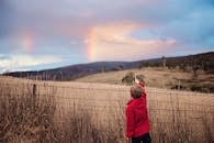 Boy Standing Near Fence Pointing on the Sky