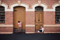 Two Children Standing and Sitting Beside Doors