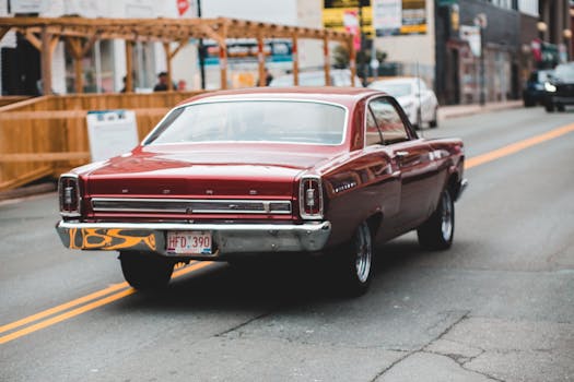 Rear view of a vintage red car driving on a city street, emphasizing urban nostalgia.