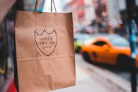 Paper bag with label on blurred background of pavement near road with cars