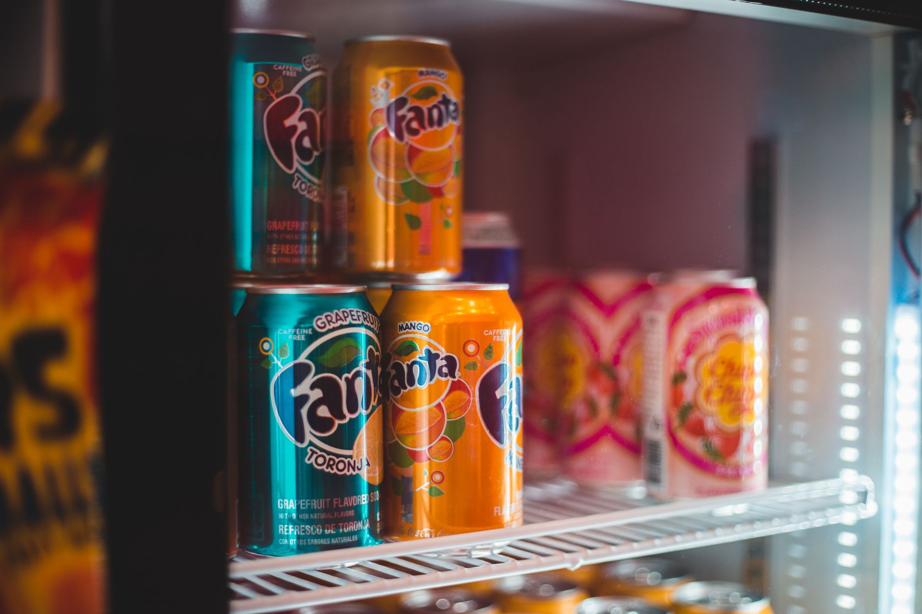 Colorful bottles with different fruit flavored carbonated soft drinks placed in fridge in supermarket