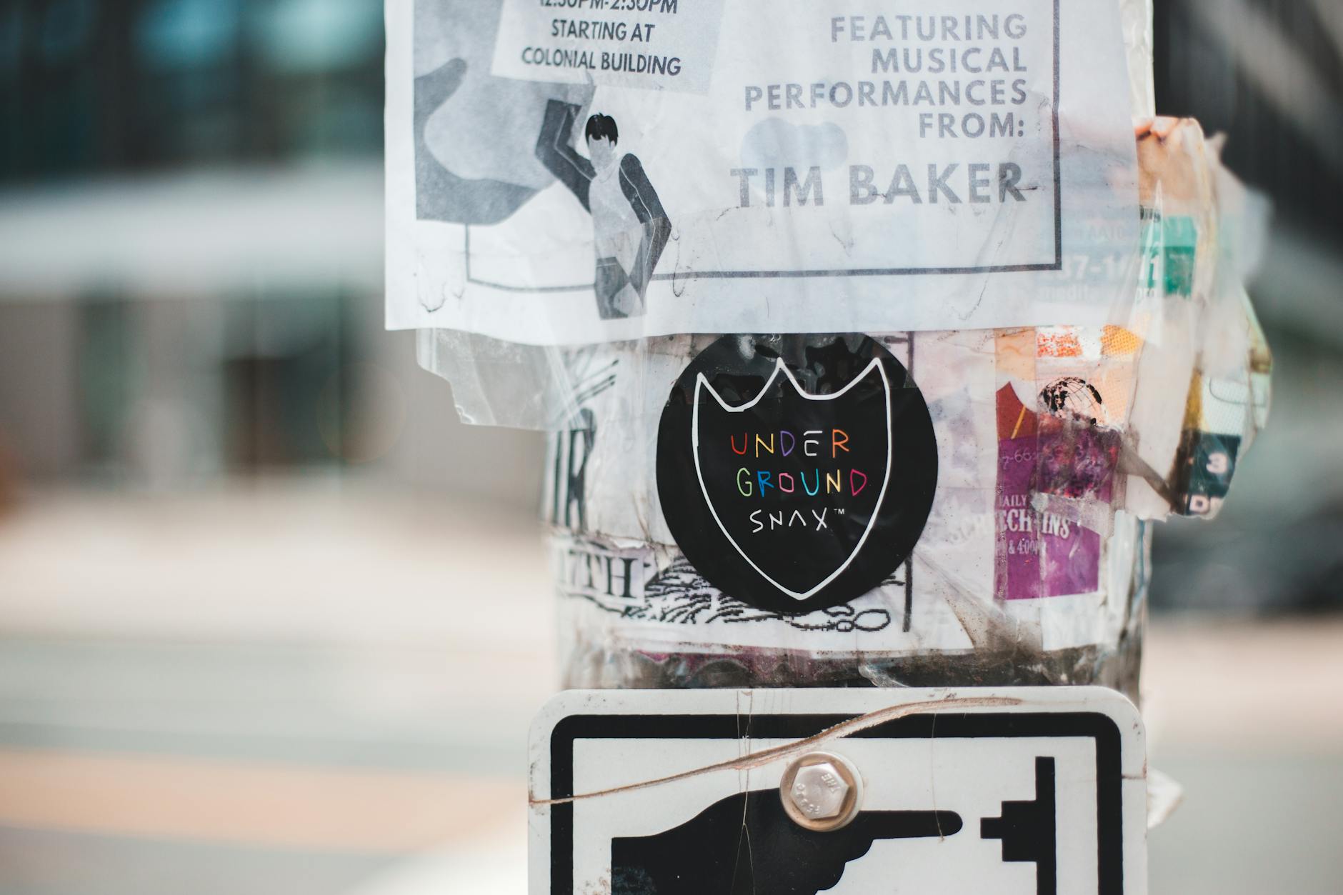 Metal street pole covered with different stickers and ads placed on street in daytime