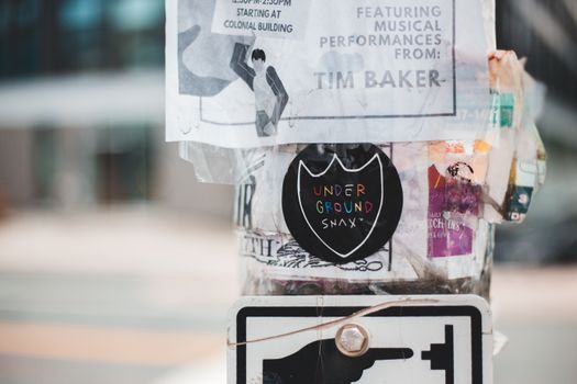Metal street pole covered with different stickers and ads placed on street in daytime