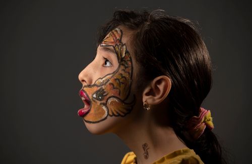 Free Side view portrait of a woman with colorful artistic fish face paint and accessories. Stock Photo